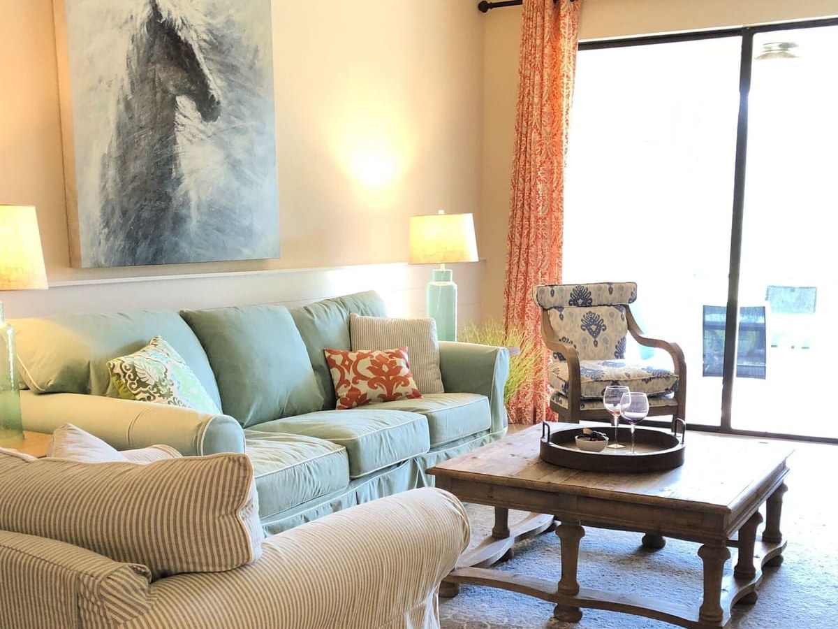 Living room with a slipcovered sofa and coffee table, sliding doors out to the screened porch